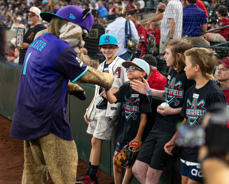 Baxter, the Arizona Diamondbacks mascot, shares a fun moment with excited Kids Take the Field participants, bringing smiles and excitement to an unforgettable day at Chase Field.