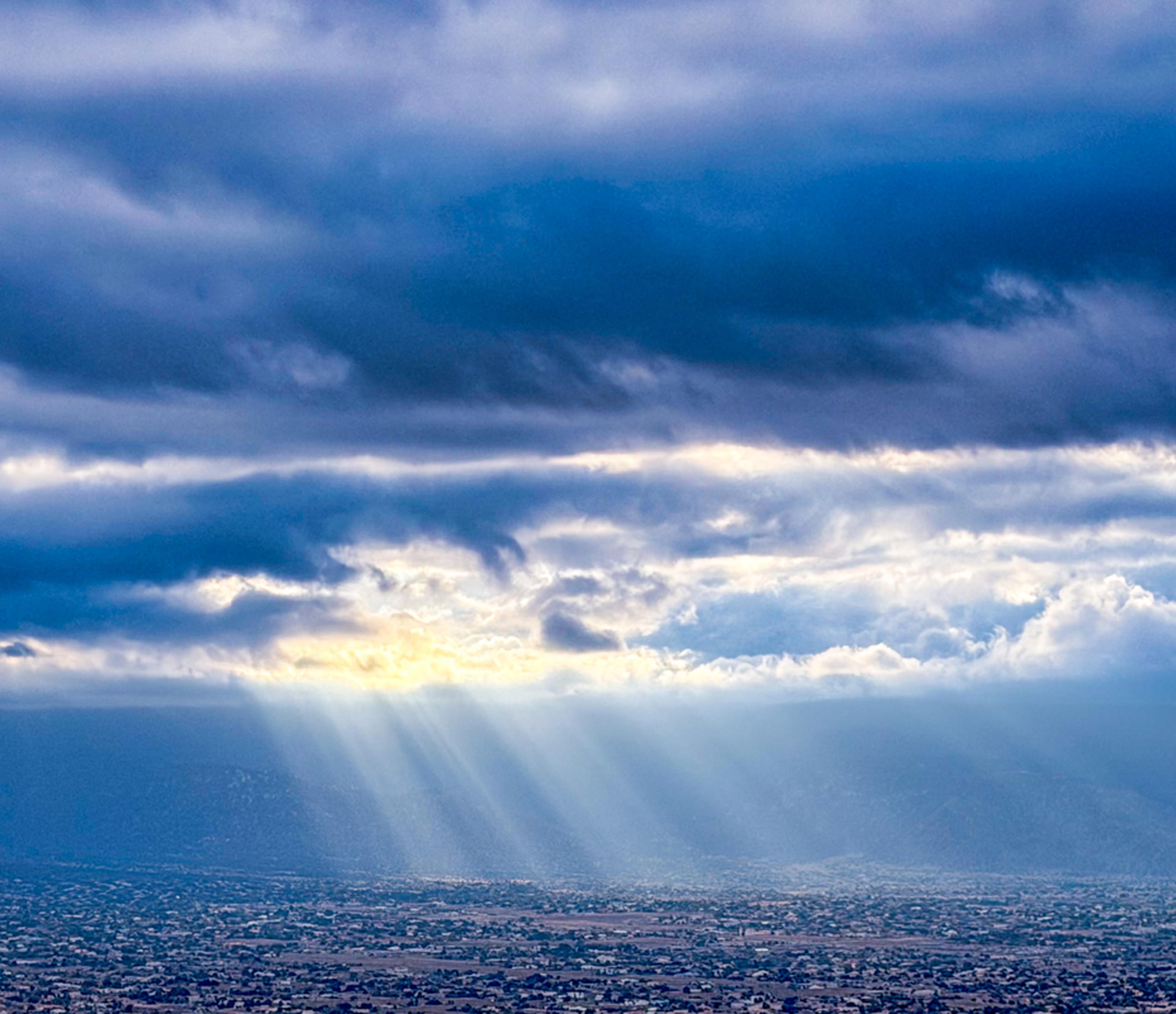 Sunbeams break through dramatic clouds, casting light across the landscape and creating a breathtaking view over Albuquerque during the International Balloon Fiesta.