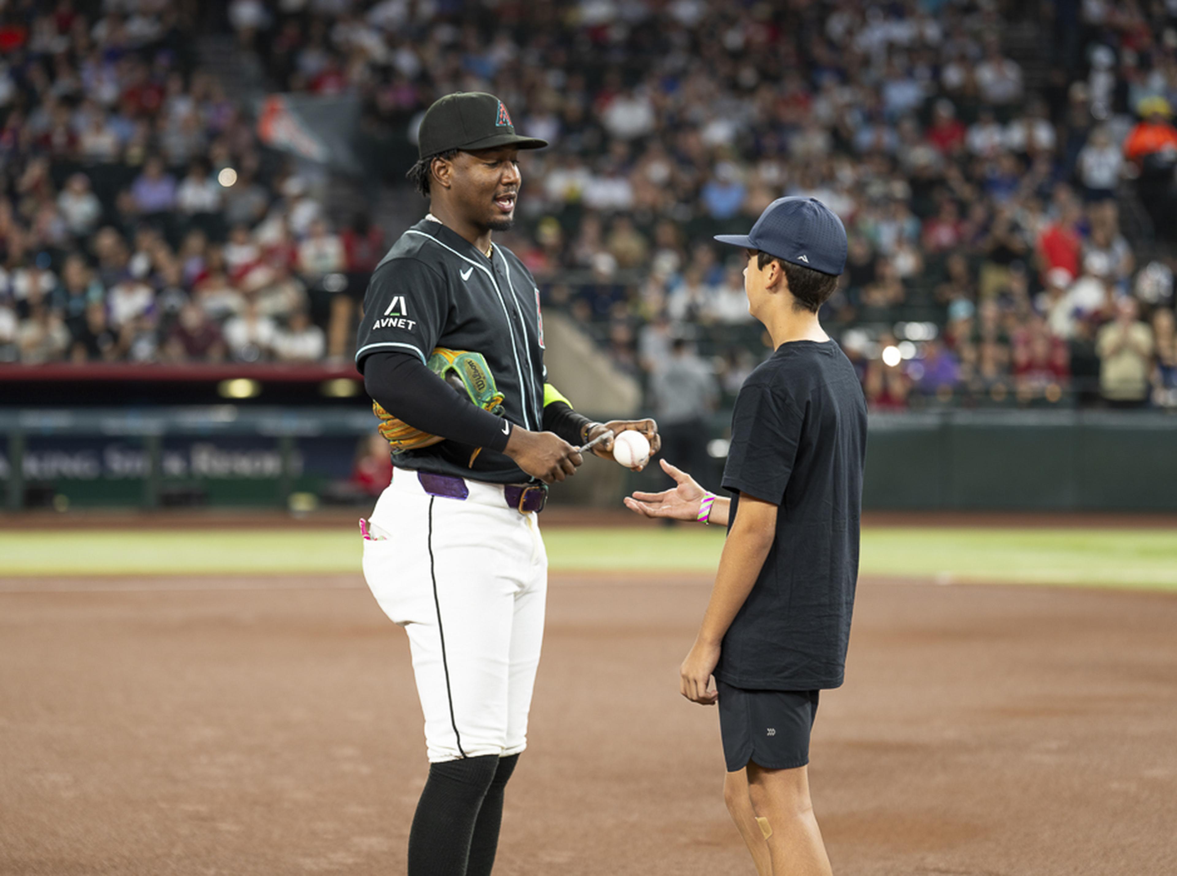A young fan receives a baseball from an Arizona Diamondbacks player on the field, creating a once-in-a-lifetime memory during his unforgettable Kids Take the Field experience at Chase Field.
