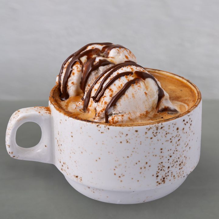 A mug with an espresso drink topped with two scoops of vegan coconut oat gelato and a drizzle of organic chocolate hazelnut syrup.