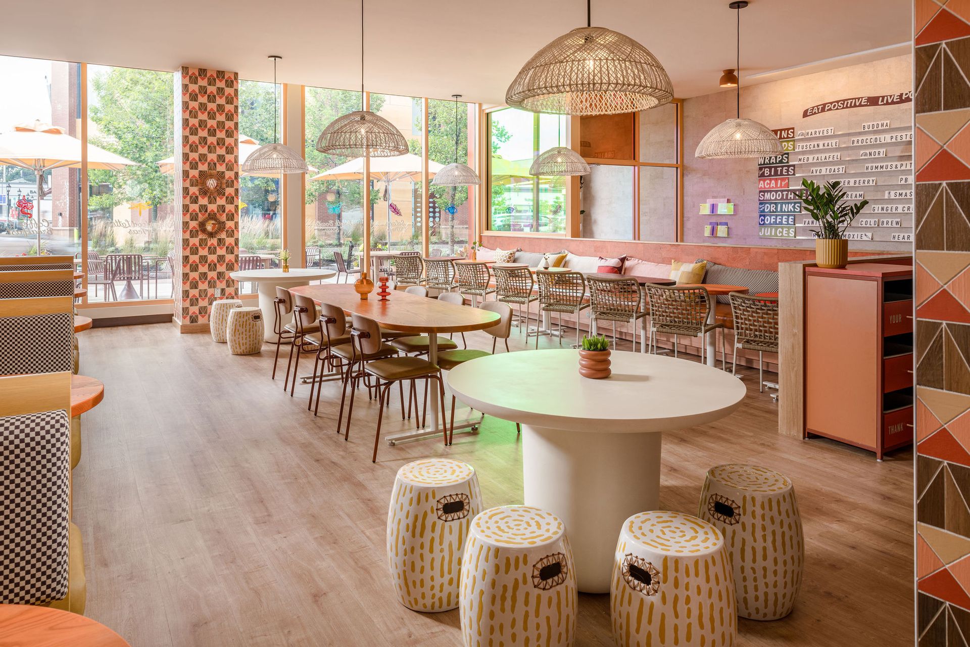 The Legacy Place Cafe dining room streaming with natural light and beautiful tables and chairs in tan, yellow and orange tones.