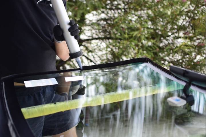 Technician applying urethane to a car windscreen aperture