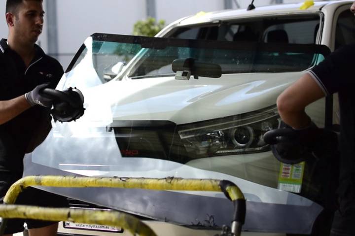Technicians removing a damaged car windscreen