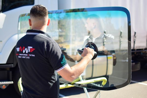 Technician fitting a new windscreen to a truck cab