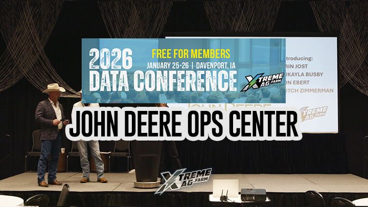 Three people onstage at the 2026 Data Conference in Davenport, IA, with a large screen displaying event details and sponsors.