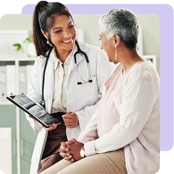A doctor holding a tablet discusses with a smiling patient in an office setting.