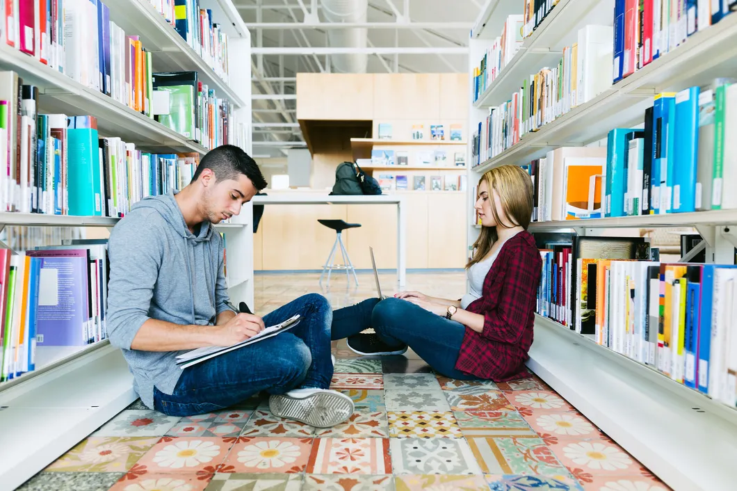 Man and woman at library, sitting on floor working