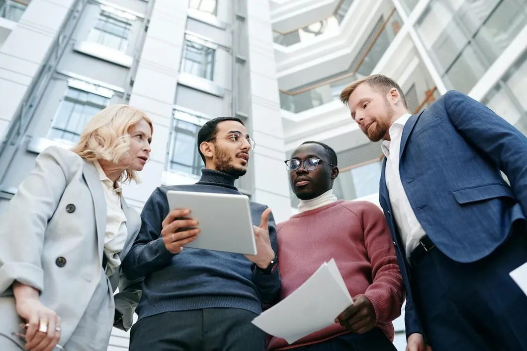 group-standing-together-discussing-something-on-tablet