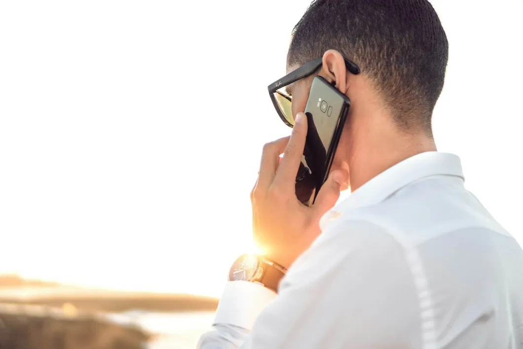 Man in white shirt speaking on his cell phone with his back unturned to the camera