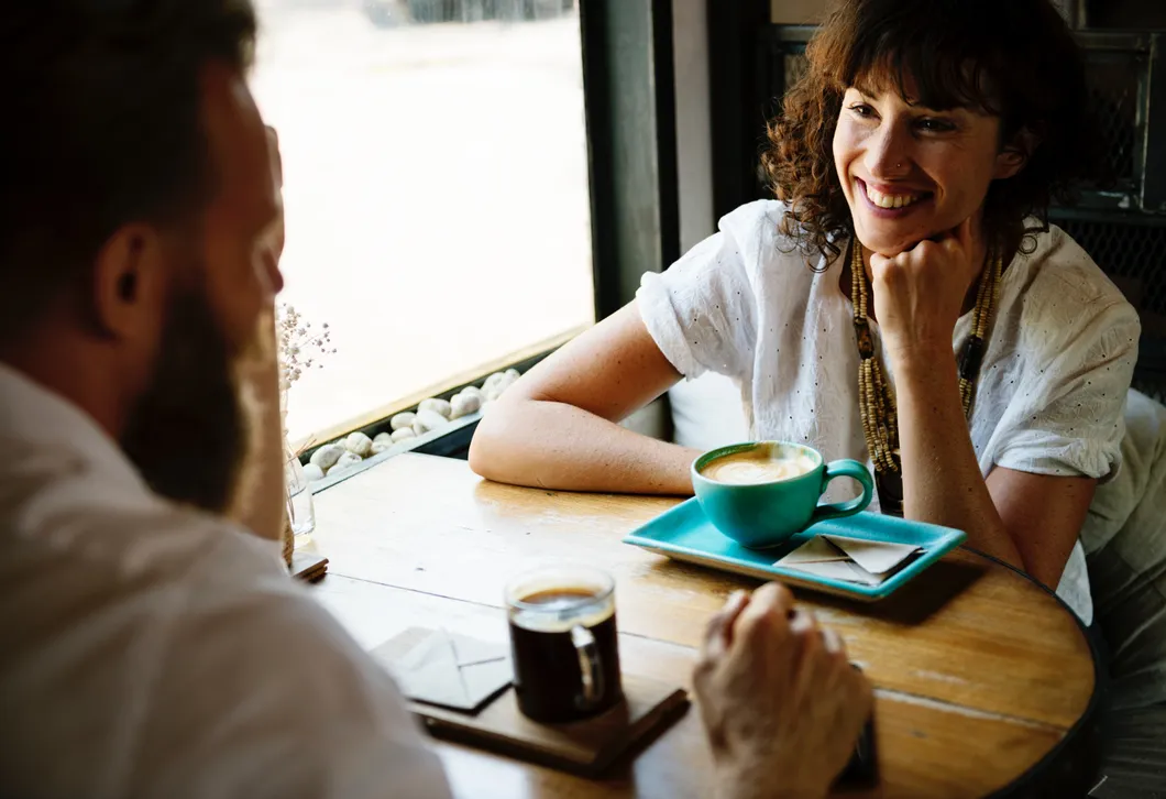 Two people meeting over coffee to discuss education funding and financial planning options.
