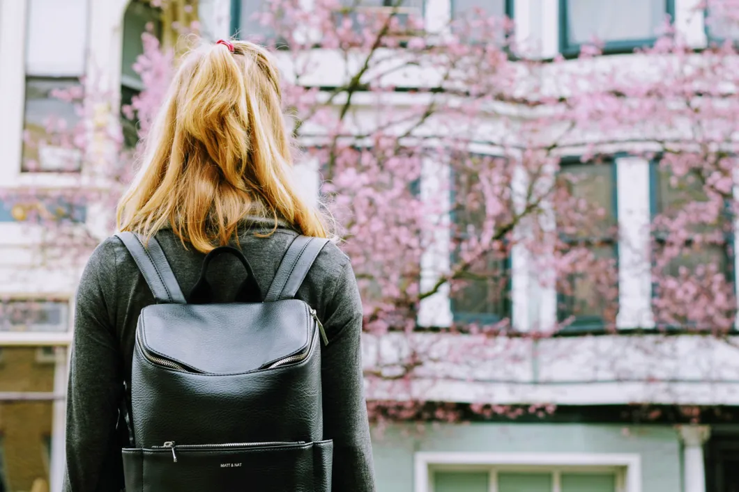 Woman wearing backpack facing building