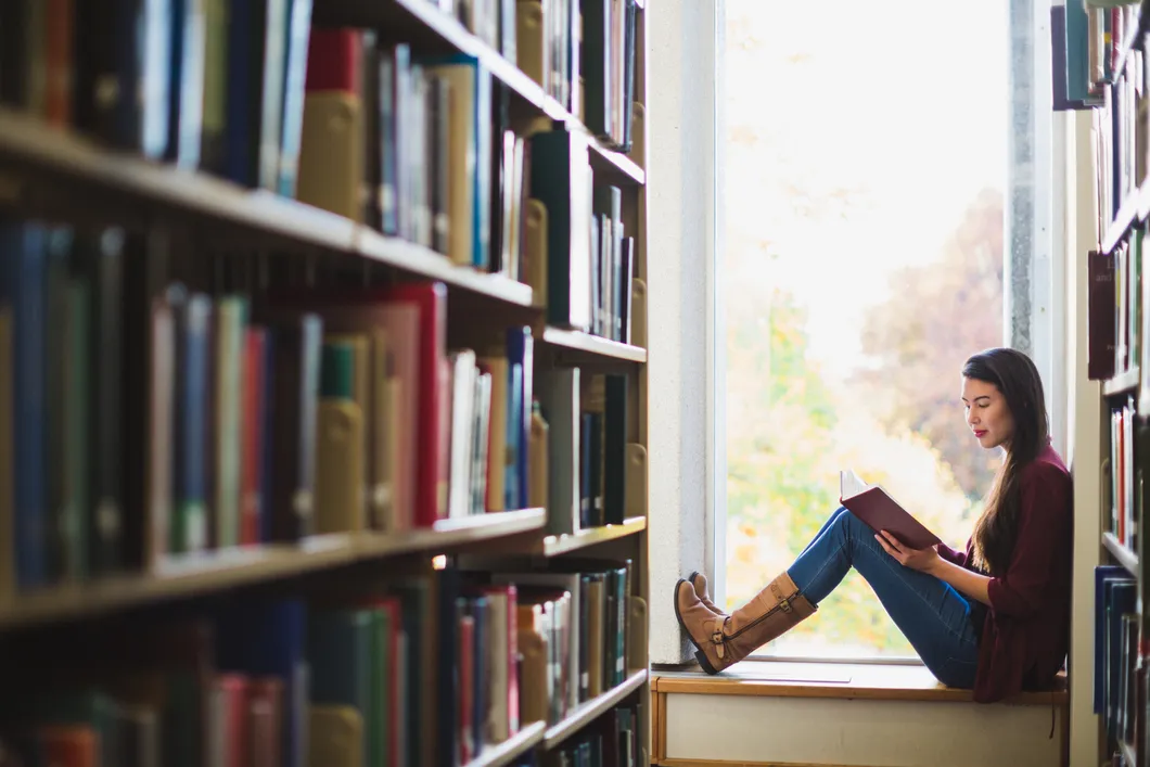 woman-in-library-reading-by-window
