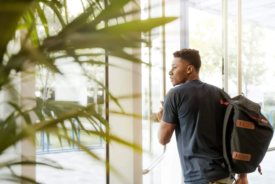 Man wearing backpack, walking out of build doors