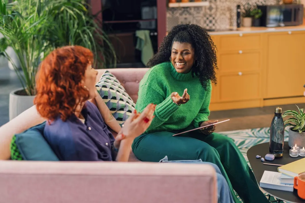 Two women sitting on a couch talking and laughing