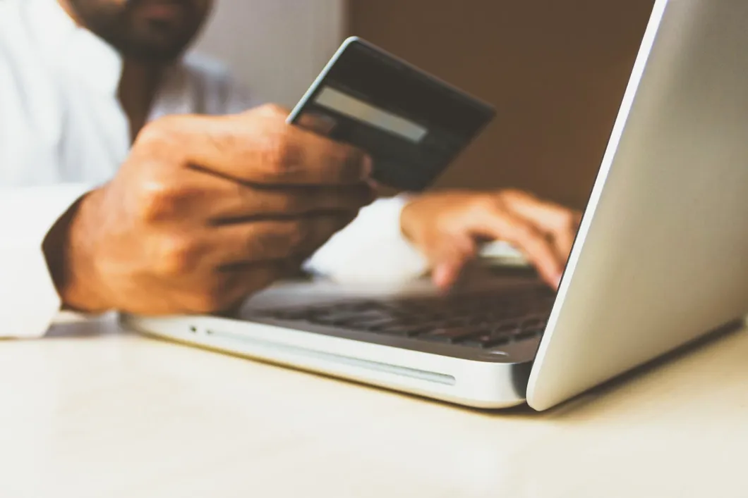 man-typing-on-laptop-looking-at-credit-card