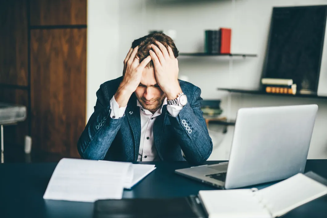 man-with-head-in-hands-looking-at-documents