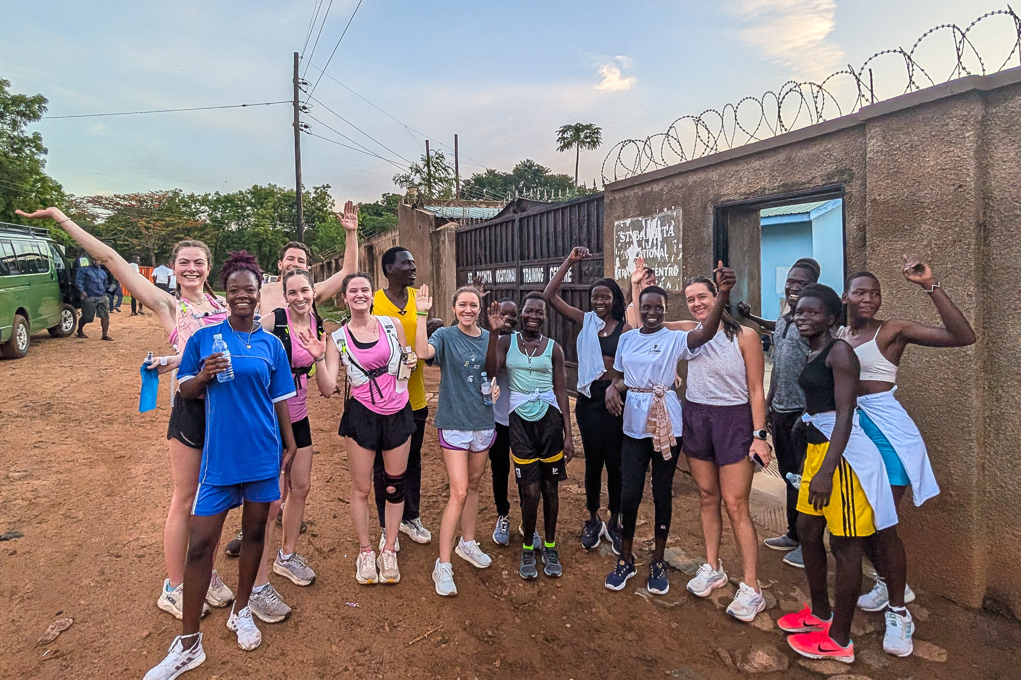 Group of diverse runners smiling and posing outside a training center, with a mix of athletic clothing and a lively, energetic atmosphere.
