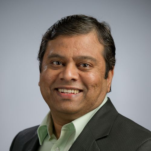 Notre Dame Professor Sarv Devaraj in a suit with a light green shirt, against a plain gray background.