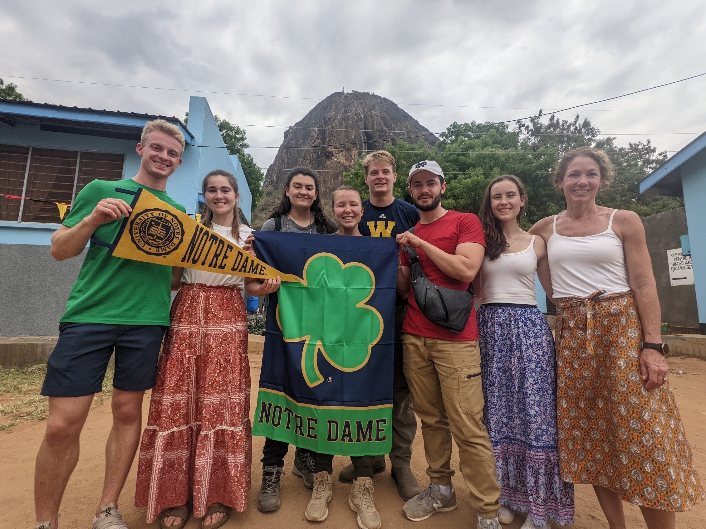 Notre Dame students and professor pose with ND flags at Saint Bakhita Vocational Training Center