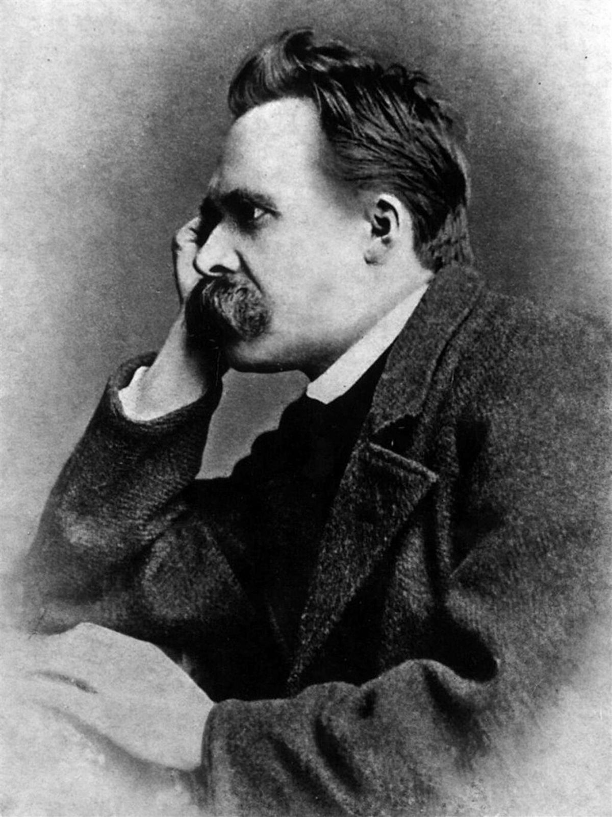 A black and white photo of Frederick Nietzsche, taken in profile. He is resting his head on his hand and has a very bushy mustache and a slightly receding hairline.