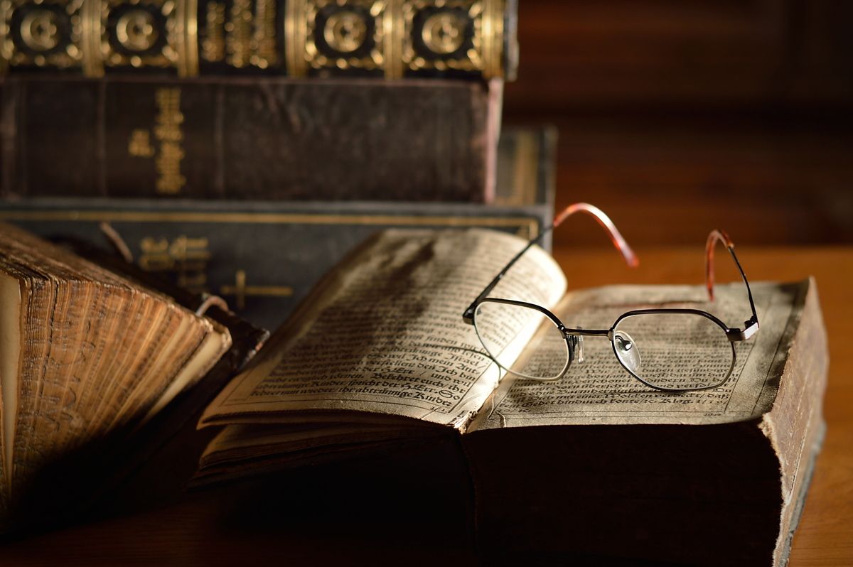 A pair of glasses sits on an old bible.