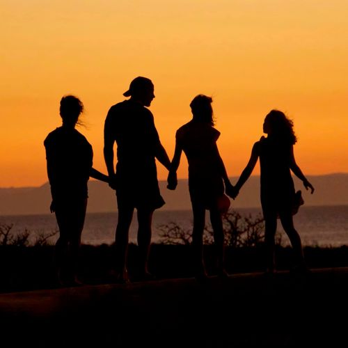 A silhouetted family stands overlooking some hills.