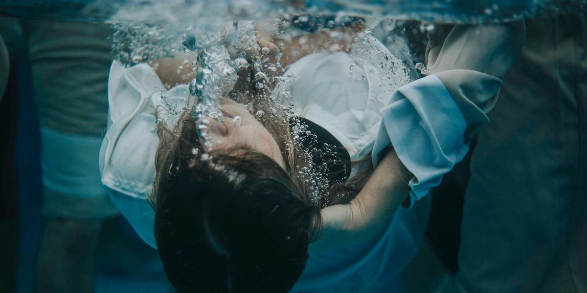 Underwater photo showing the moment a woman in a white garment is baptized.