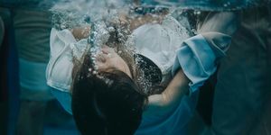 Underwater photo showing the moment a woman in a white garment is baptized.
