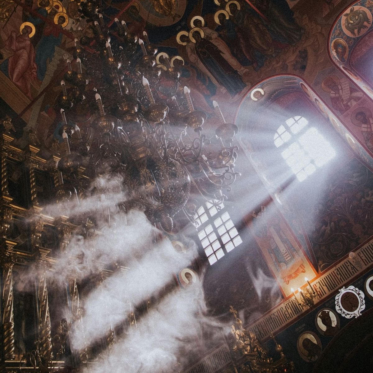 Light rays come through the windows of a dark church.