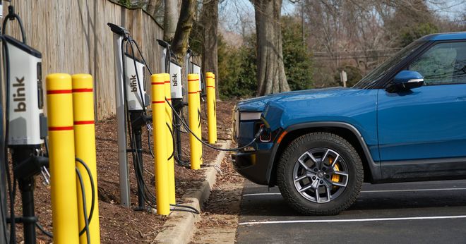 A blue electric pickup truck charges at a Blink Series 8 EV charging station