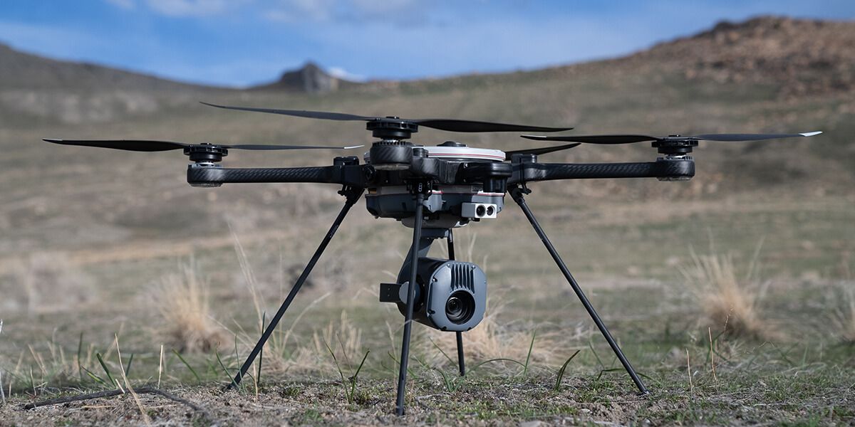 Teledyne FLIR hexacopter drone equipped with a thermal and visual inspection camera payload sitting on dry grassland terrain