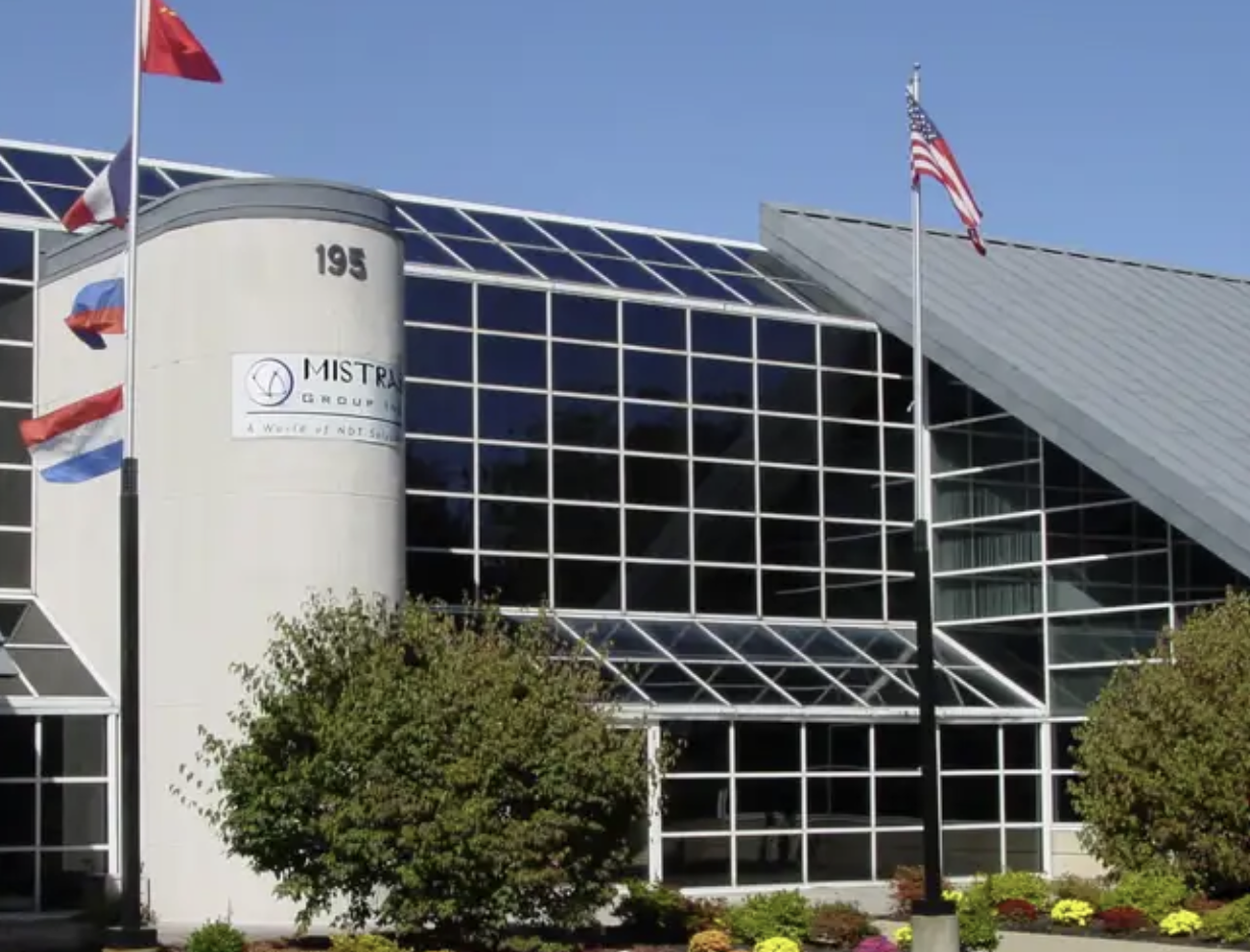 The MISTRAS Group headquarters building with flags flying in front.
