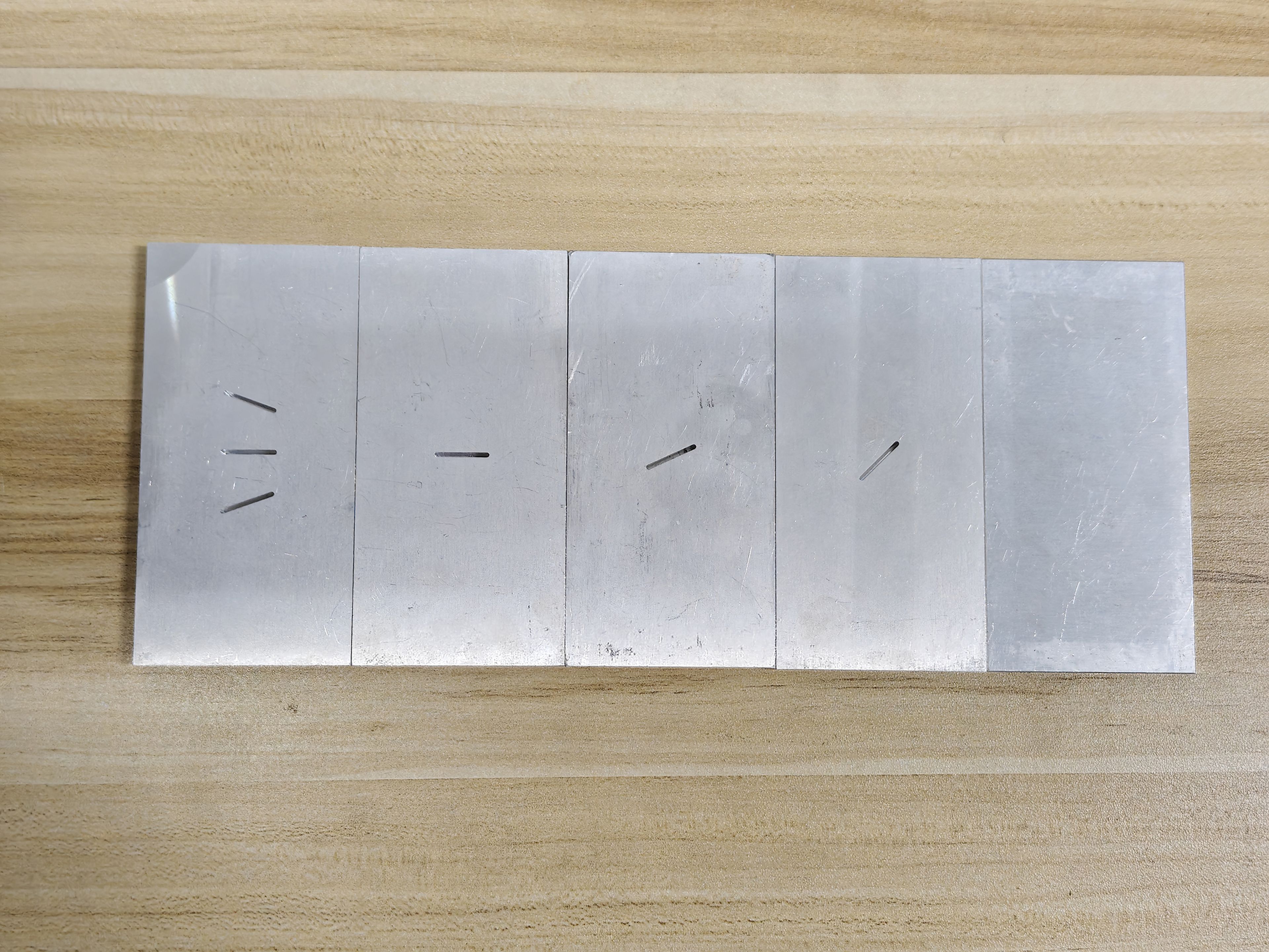 Five aluminum test specimens machined with artificial surface-breaking slot cracks at various angles, used for experimental ACFM validation.