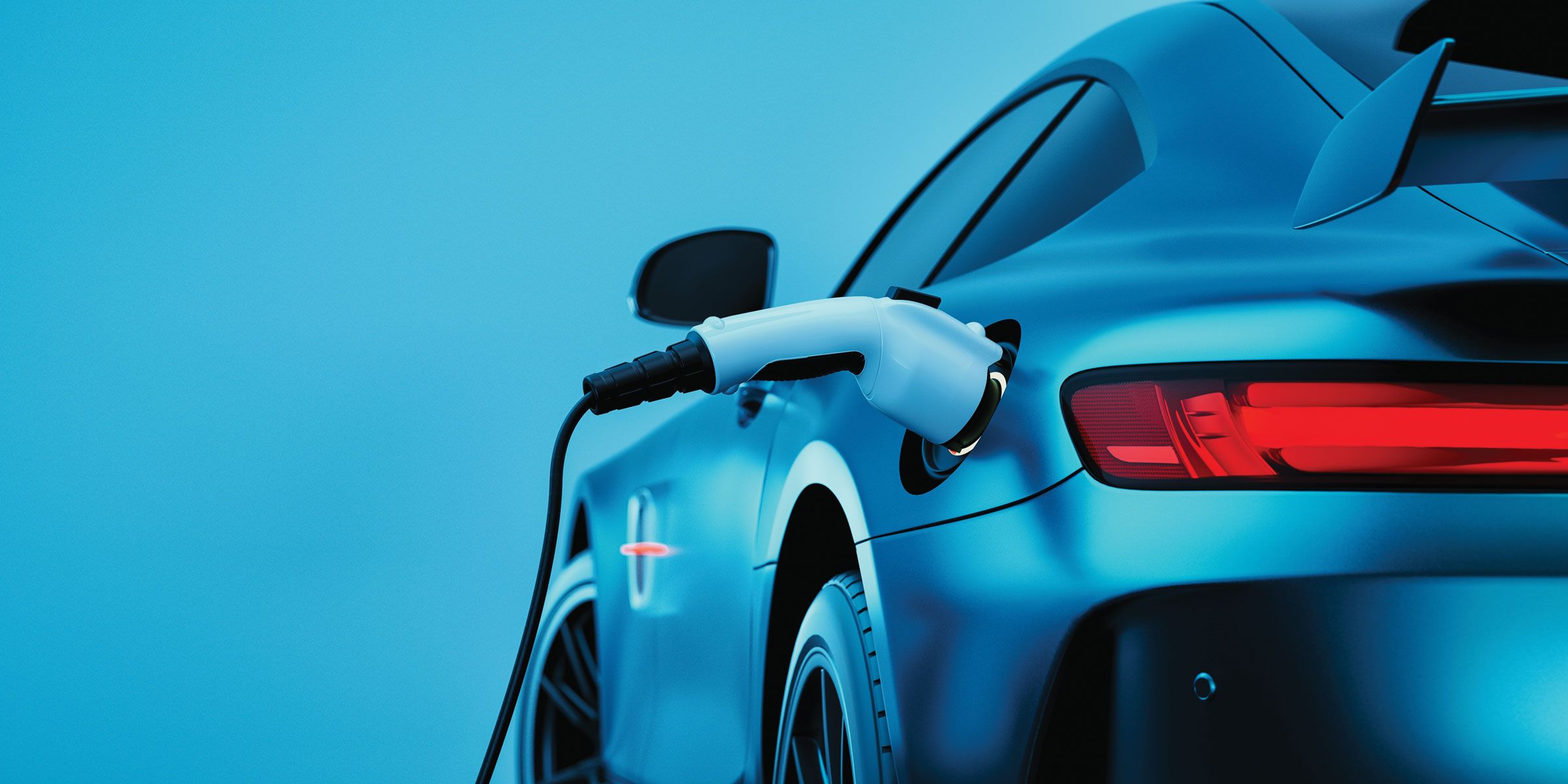 A sleek electric car charging at a station, featuring a vibrant blue color and rear taillights illuminated in a modern setting.