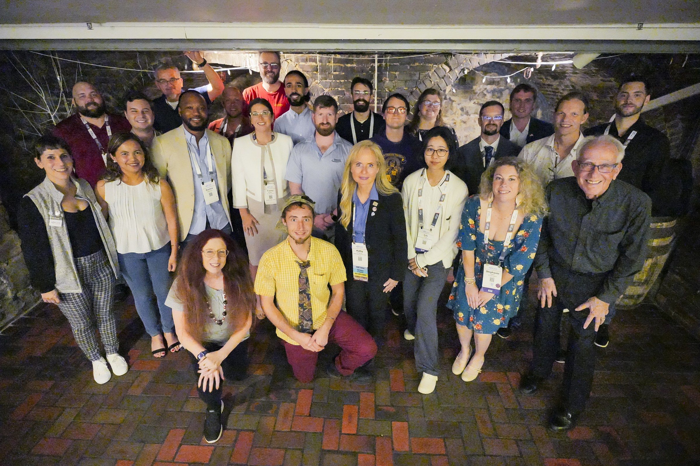 Group photo of RISE program participants, alumni, and mentors in a brick-walled brewpub