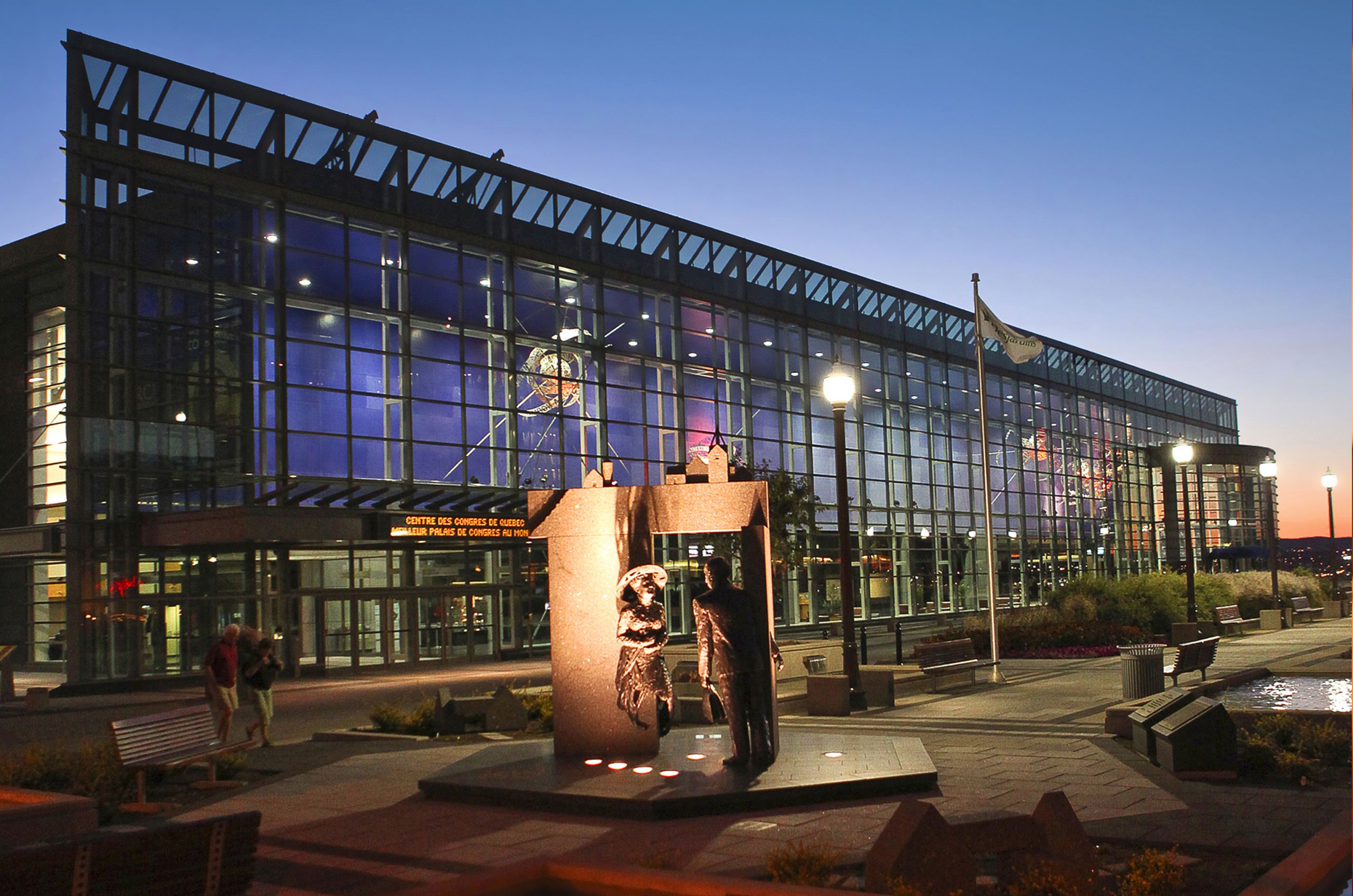 The Quebec City Convention Center with an illuminated sculpture in the foreground, under a twilight sky.