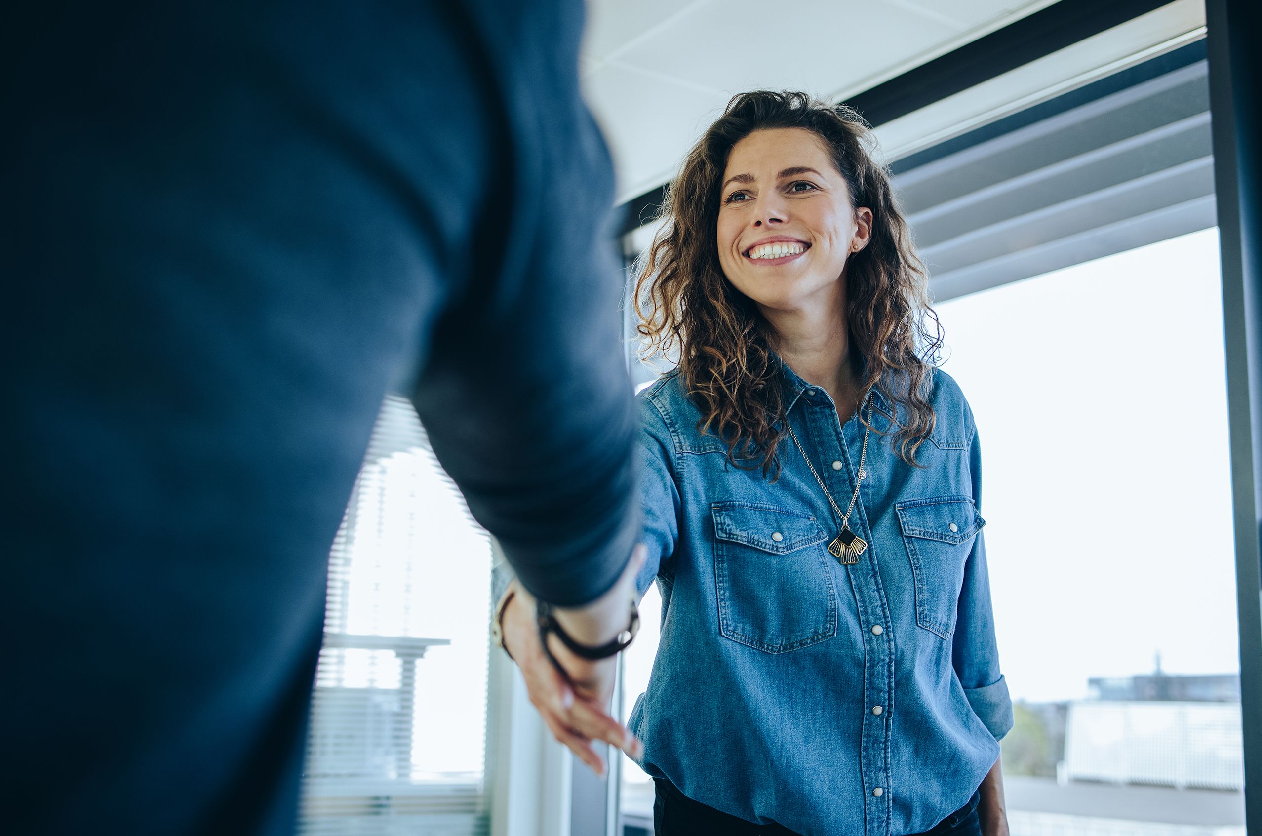 Woman smiles as she shakes a person's hand