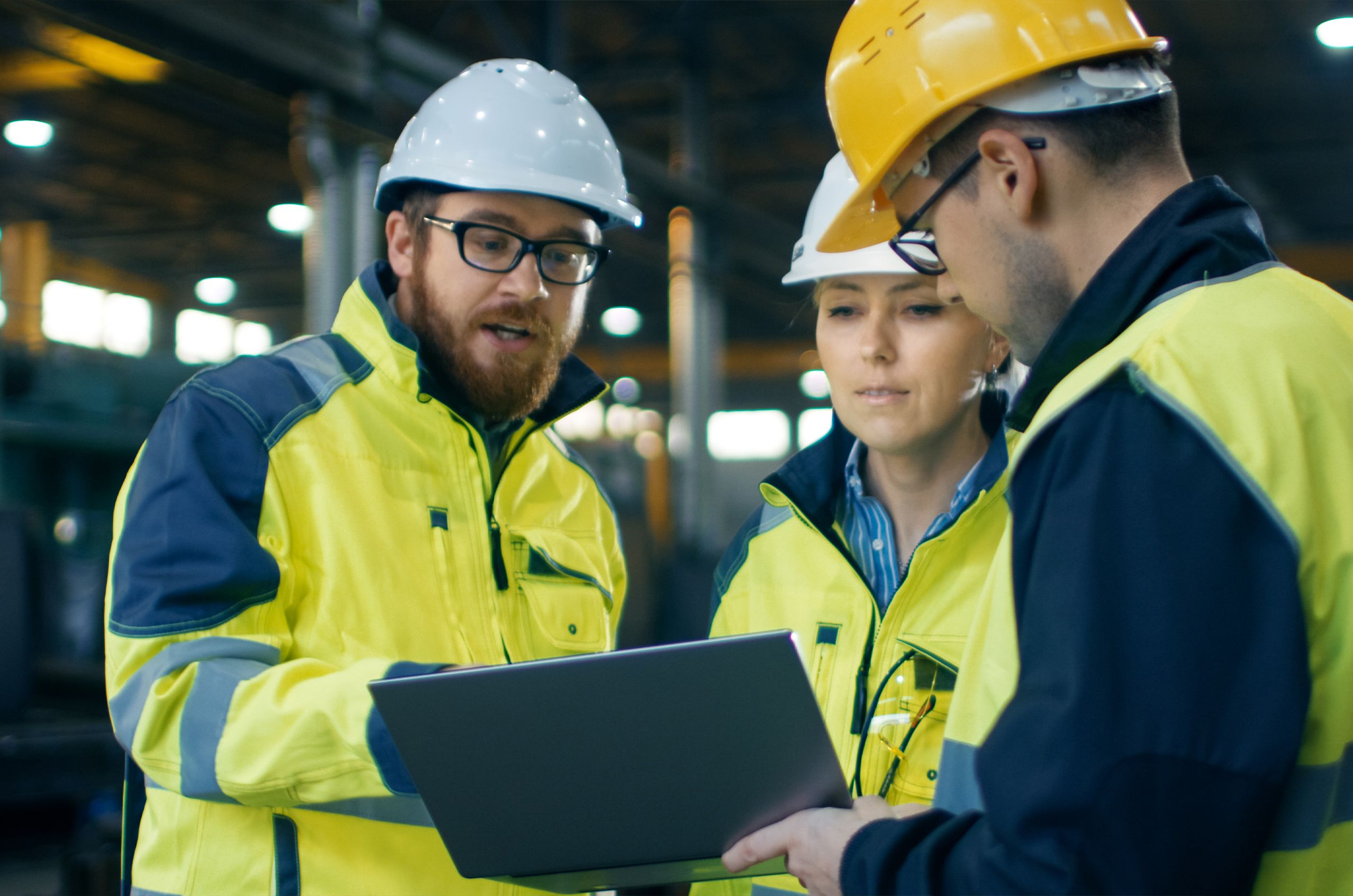 A group have a discussion standing around a tablet, all in safety gear.