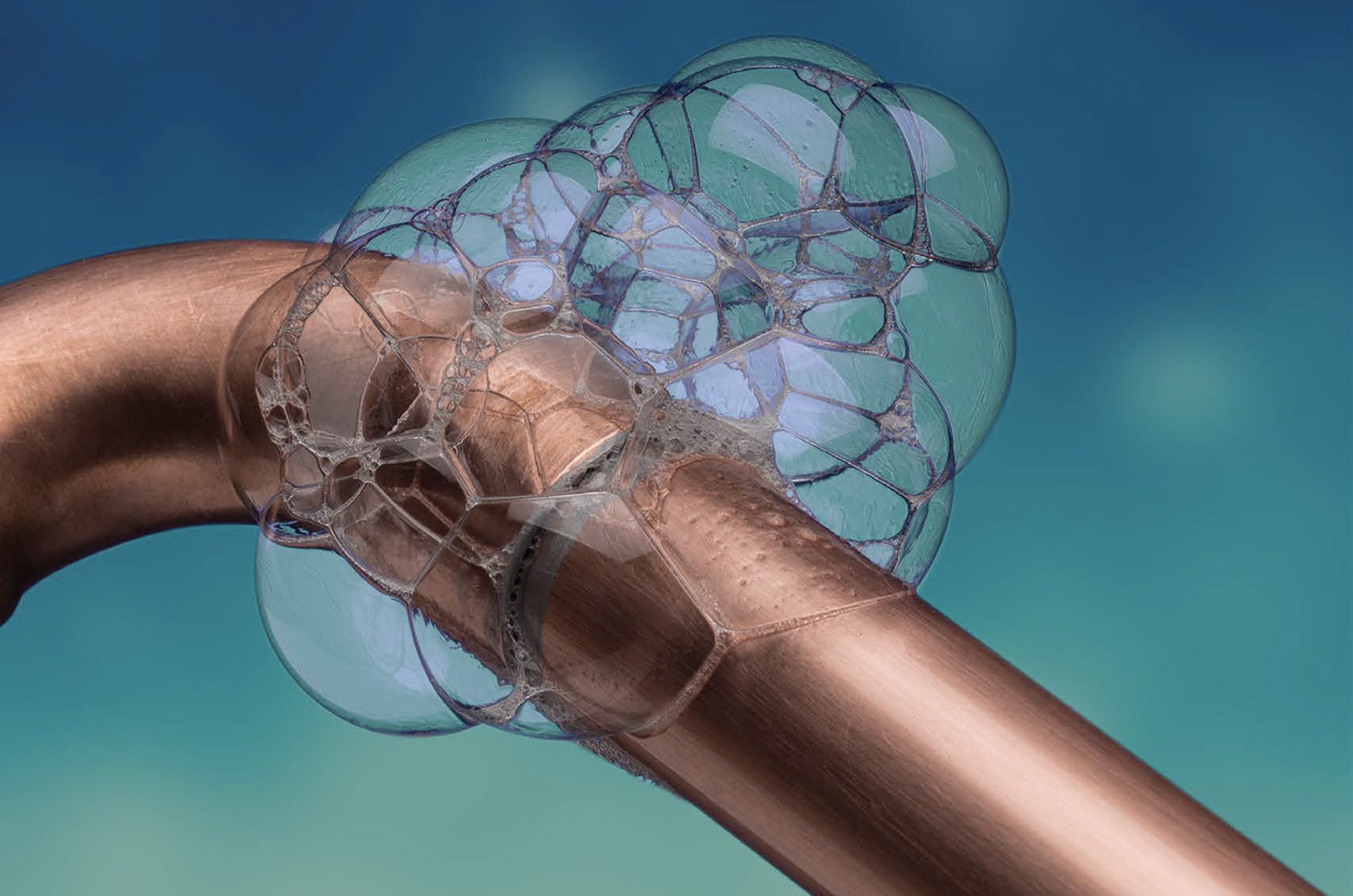Bubbles forming on a copper pipe against a soft blue background.