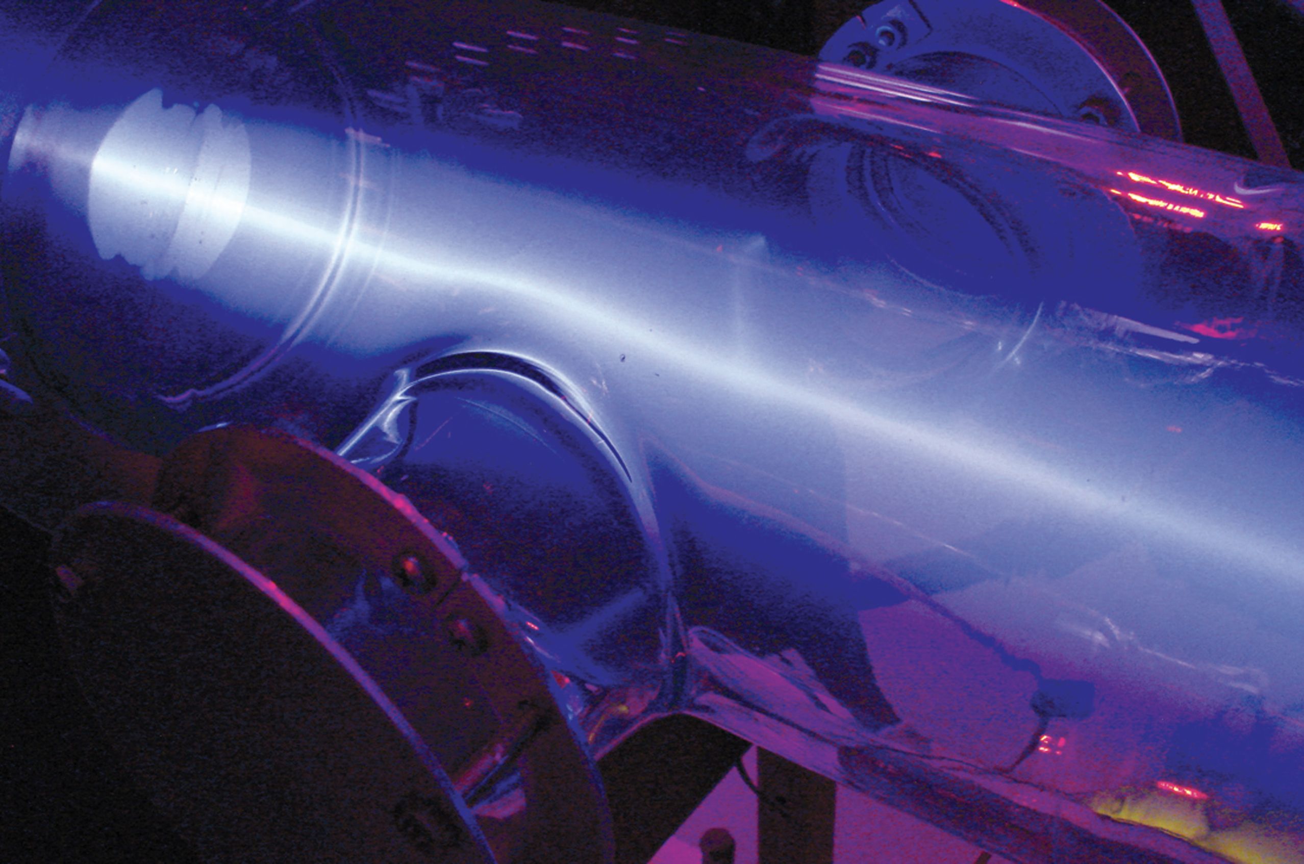 A glowing beam inside the cylindrical tube of a fusion neutron generator used to produce neutrons for radiographic inspection.