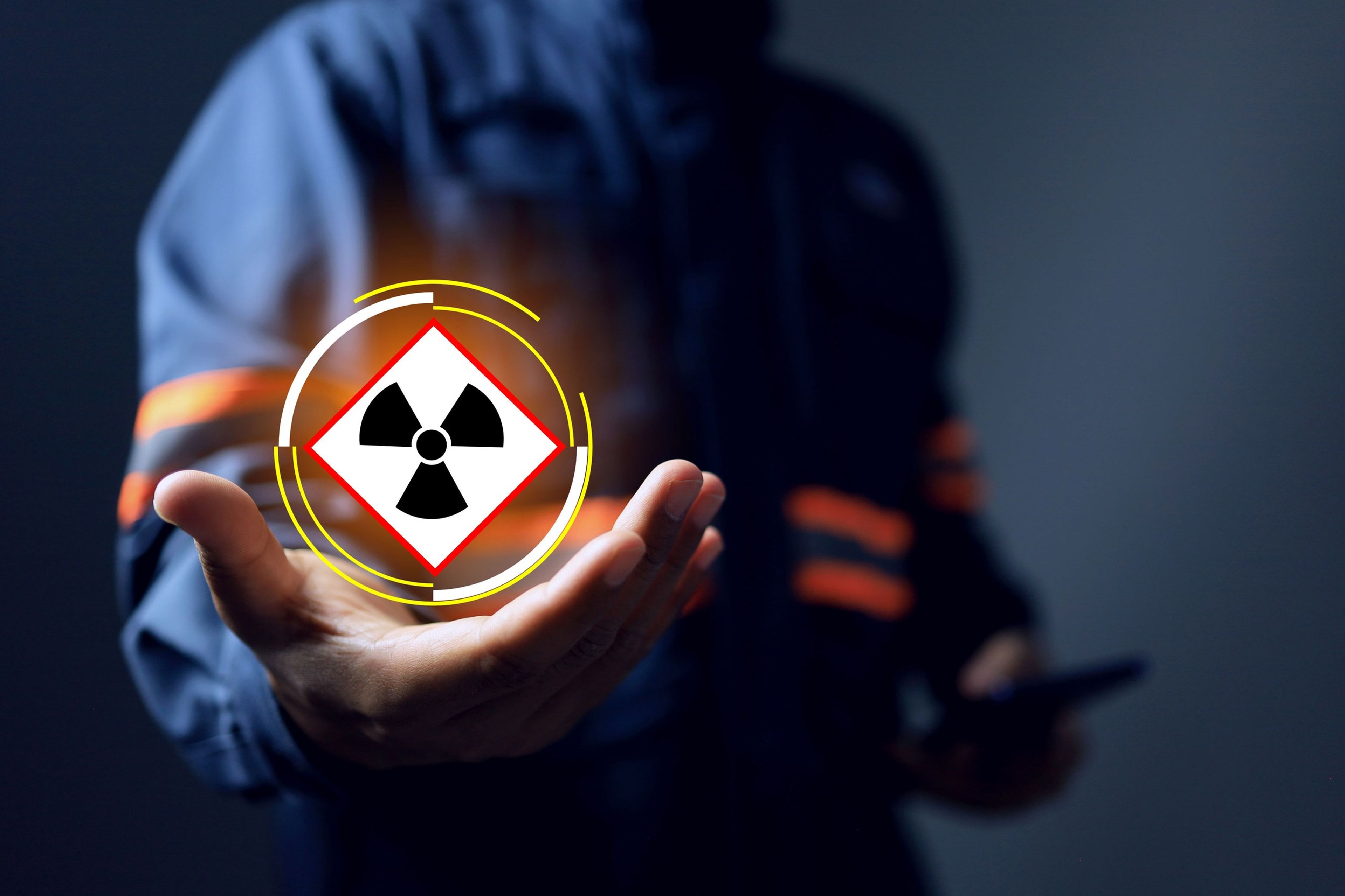 A worker holds out a hand displaying a glowing radiation-hazard warning symbol.