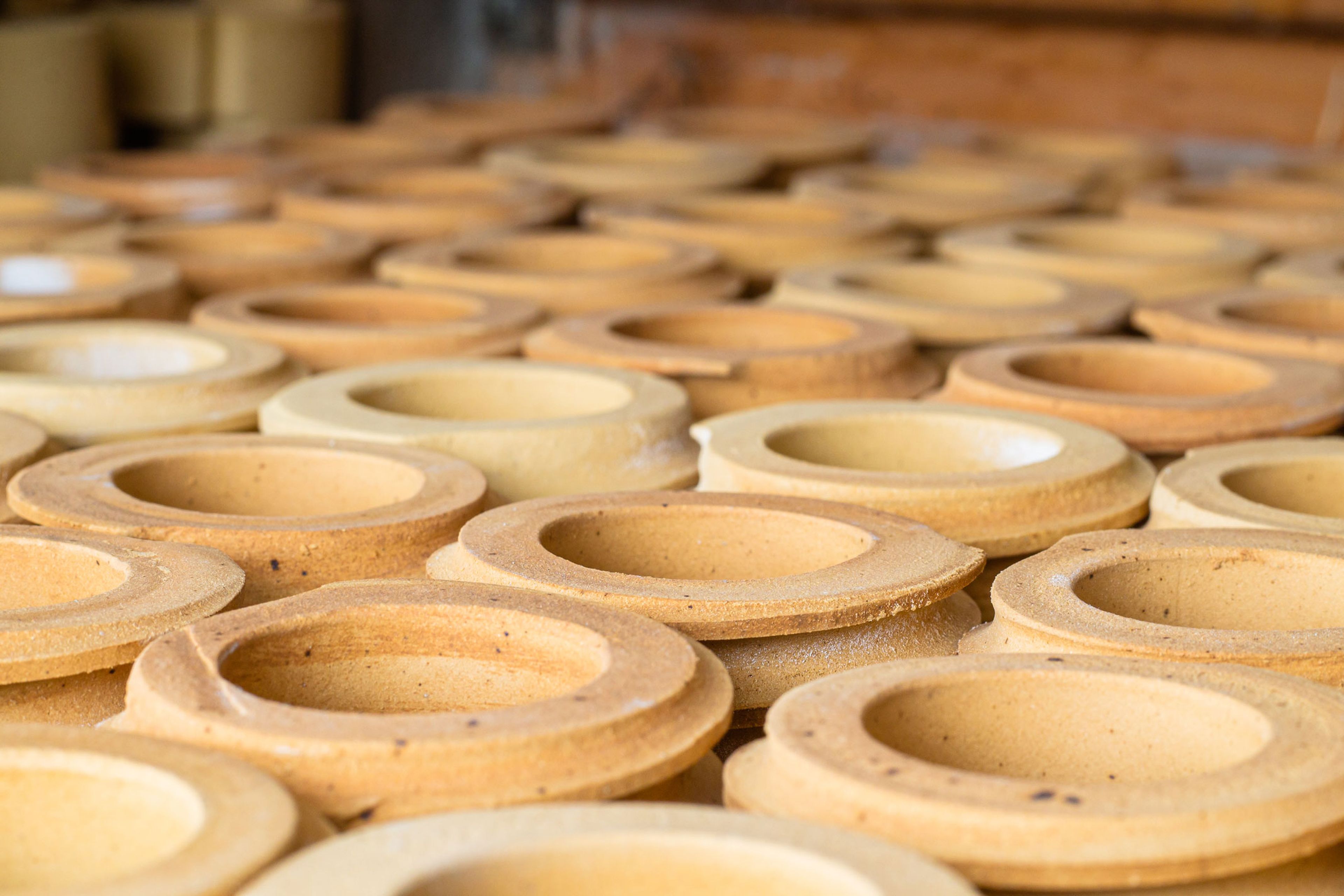 Rows of unfired ceramic ring-shaped parts arranged in a manufacturing facility.