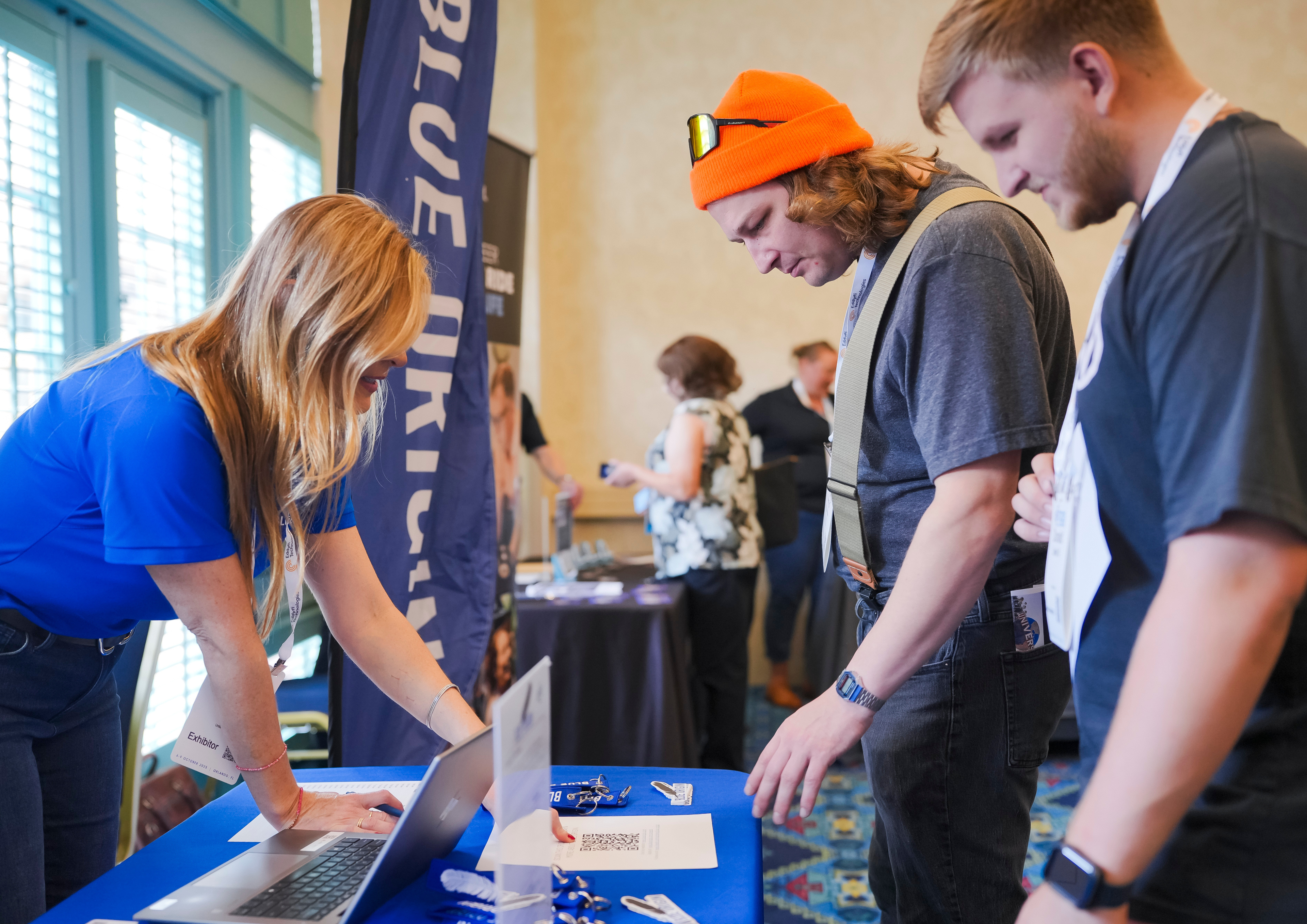 Two conference attendees speak with a company representative at a Career Corner tabling booth