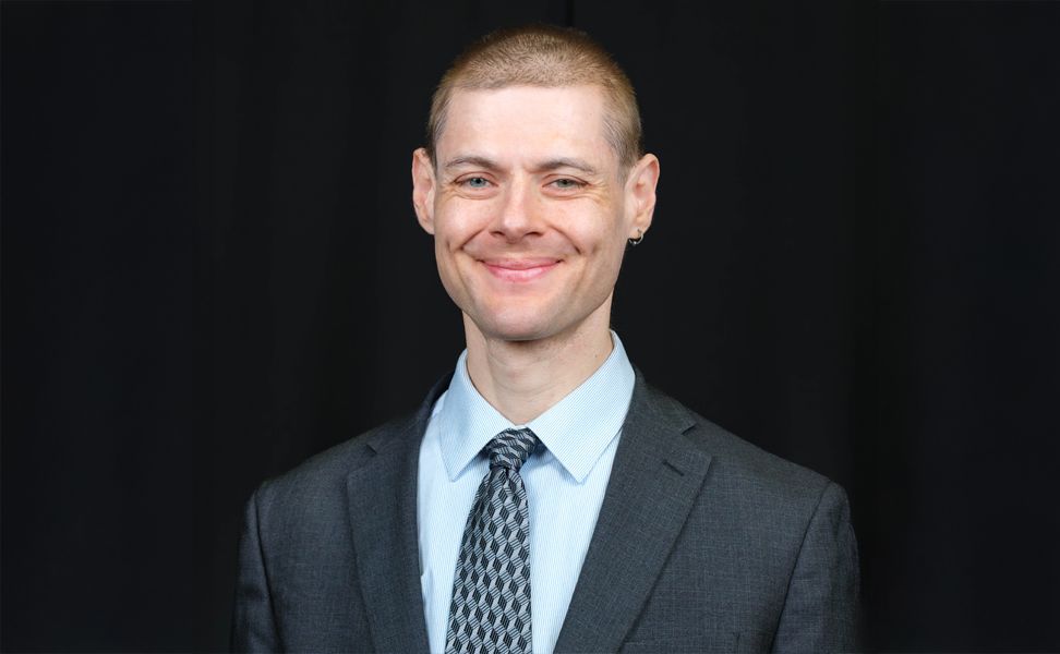 Dr. Gleb Tsipursky, smiling in front of a dark background.