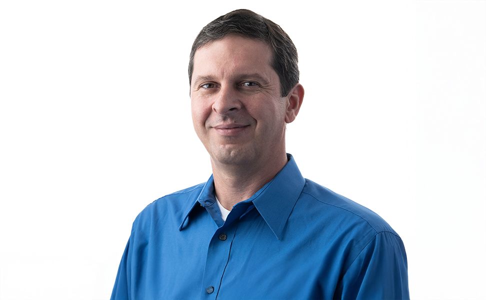 Cristian Pantea in a blue shirt with a white background, facing the camera.