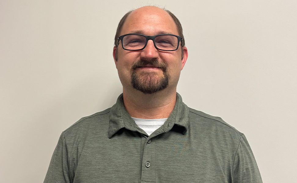 Bradley Brandt smiles at the camera. He is wearing a green polo shirt against a plain white background.