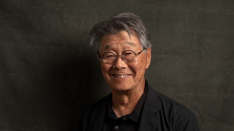 Jerry Takigawa smiling in front of a dark wall