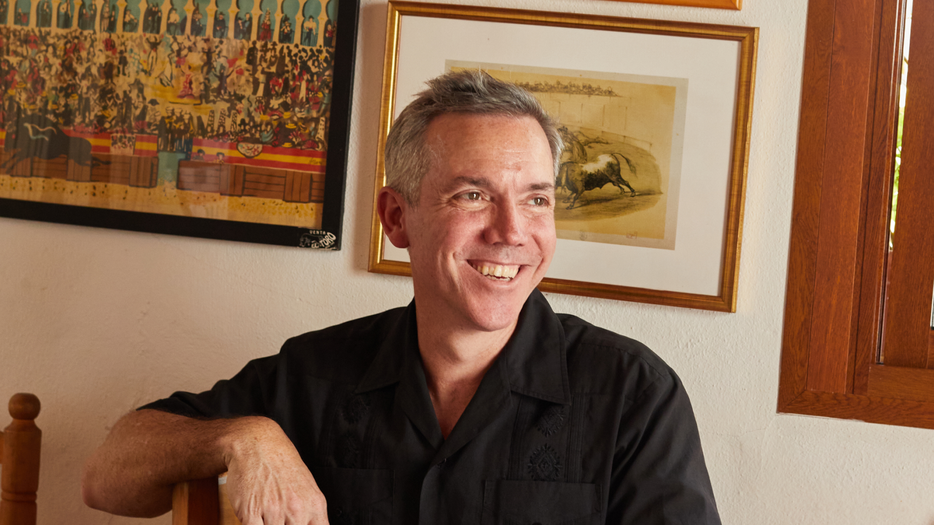 Nathan Thornburgh, seated in a room with framed art on the walls, wearing a black shirt.