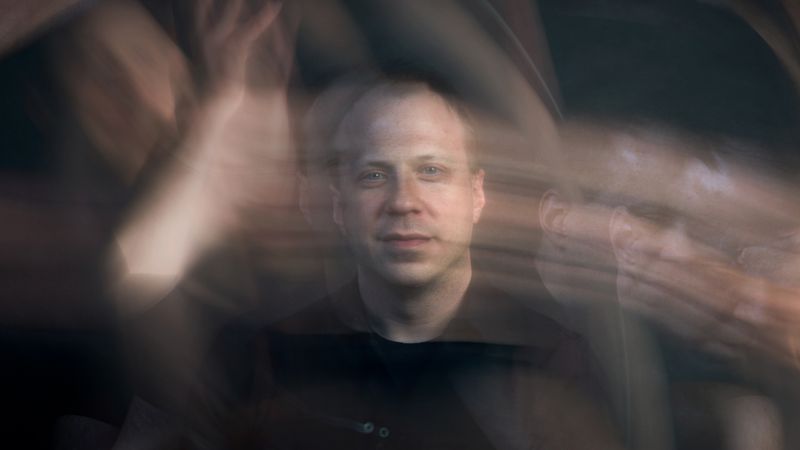 John Pobojewski surrounded by blurred motion, creating a dynamic, abstract effect.