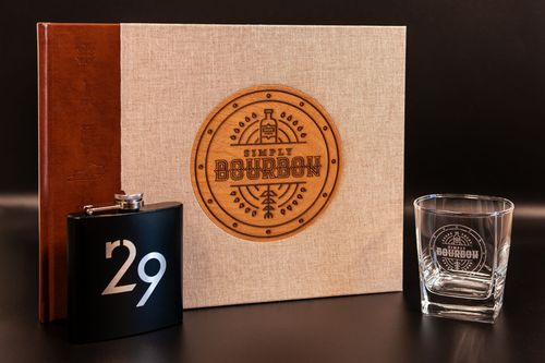 Simply Bourbon book alongside flask with R29 logo and bourbon glass with the Simply Bourbon logo